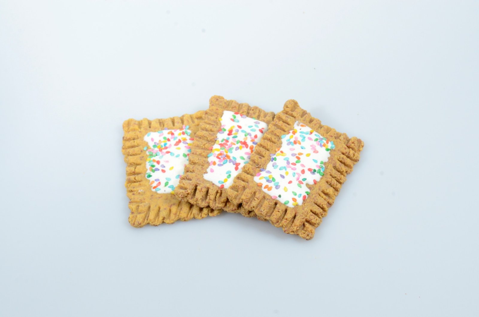 Three rectangular decorated dog treats with colorful sprinkles